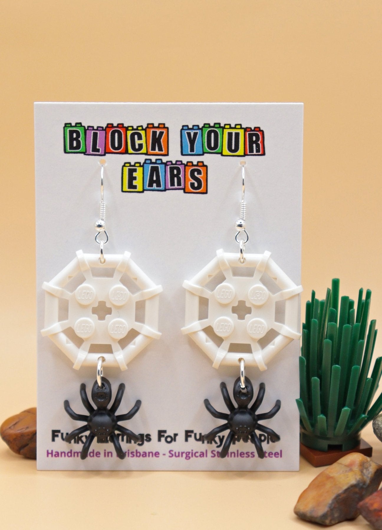 Black and white LEGO-style spider and web earrings – spooky Halloween novelty earrings on display card in desert scene