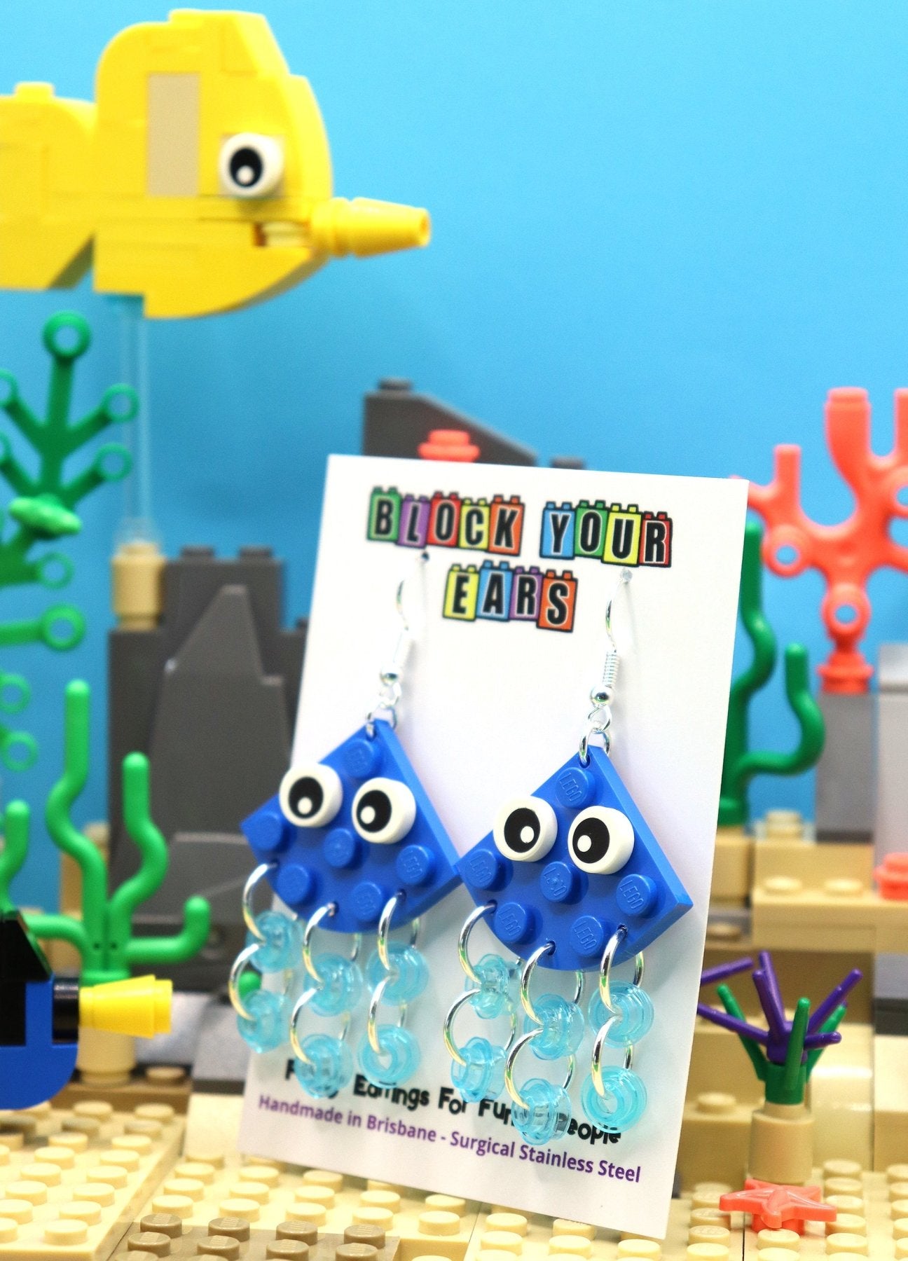 Quirky blue LEGO earrings-Jellyfish with transparent blue tentacles and cartoon eyes - display card - fish background