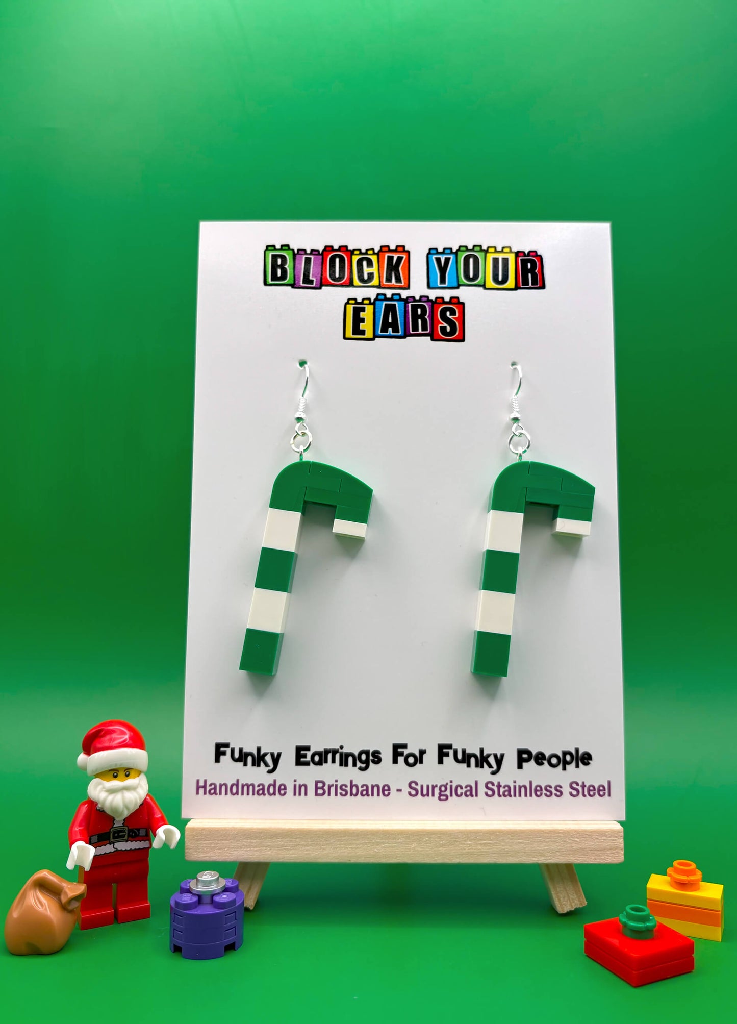 Festive green and white LEGO candy cane earrings shown on alternate display card with santa and presents