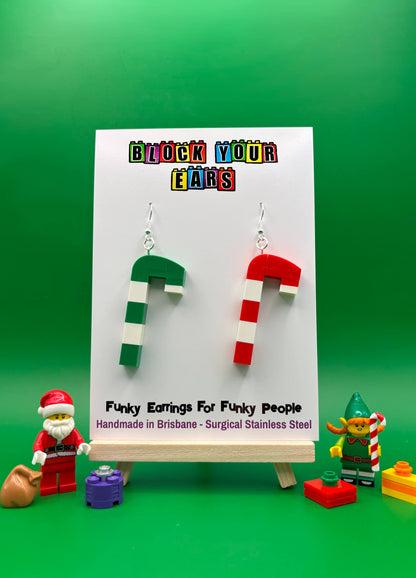 Handmade mismatched LEGO candy cane earrings on backing card, one red and white, one green and white with Santa and Elf