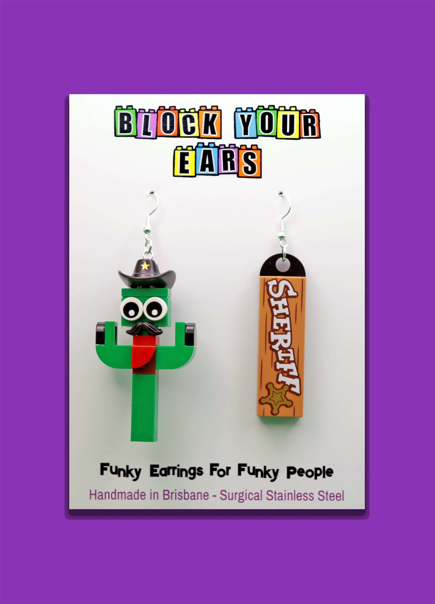 A pair of funky earrings featuring a green LEGO cactus with a black cowboy hat and red neckerchief, with 'Sheriff' tile
