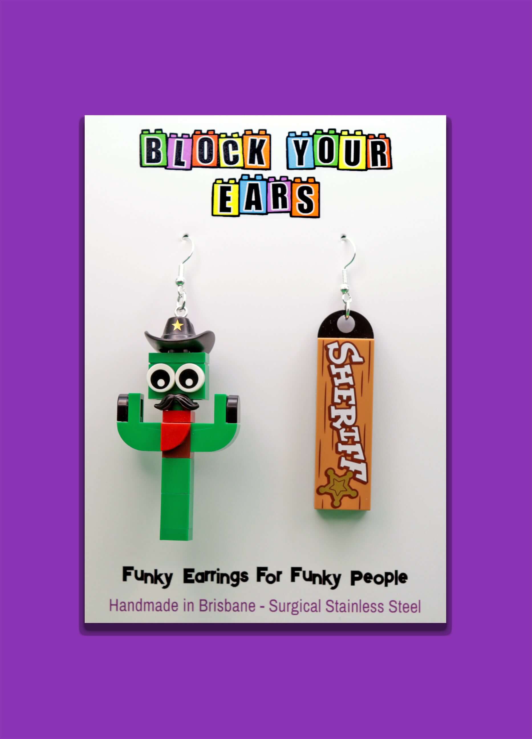 A pair of funky earrings featuring a green LEGO cactus with a black cowboy hat and red neckerchief, with 'Sheriff' tile
