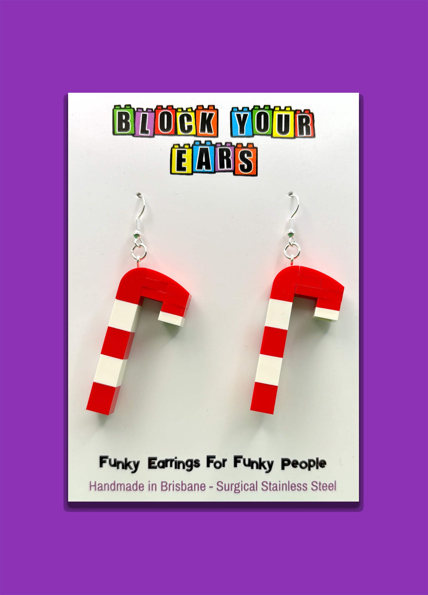 Handmade red and white LEGO candy cane earrings on display card with purple background