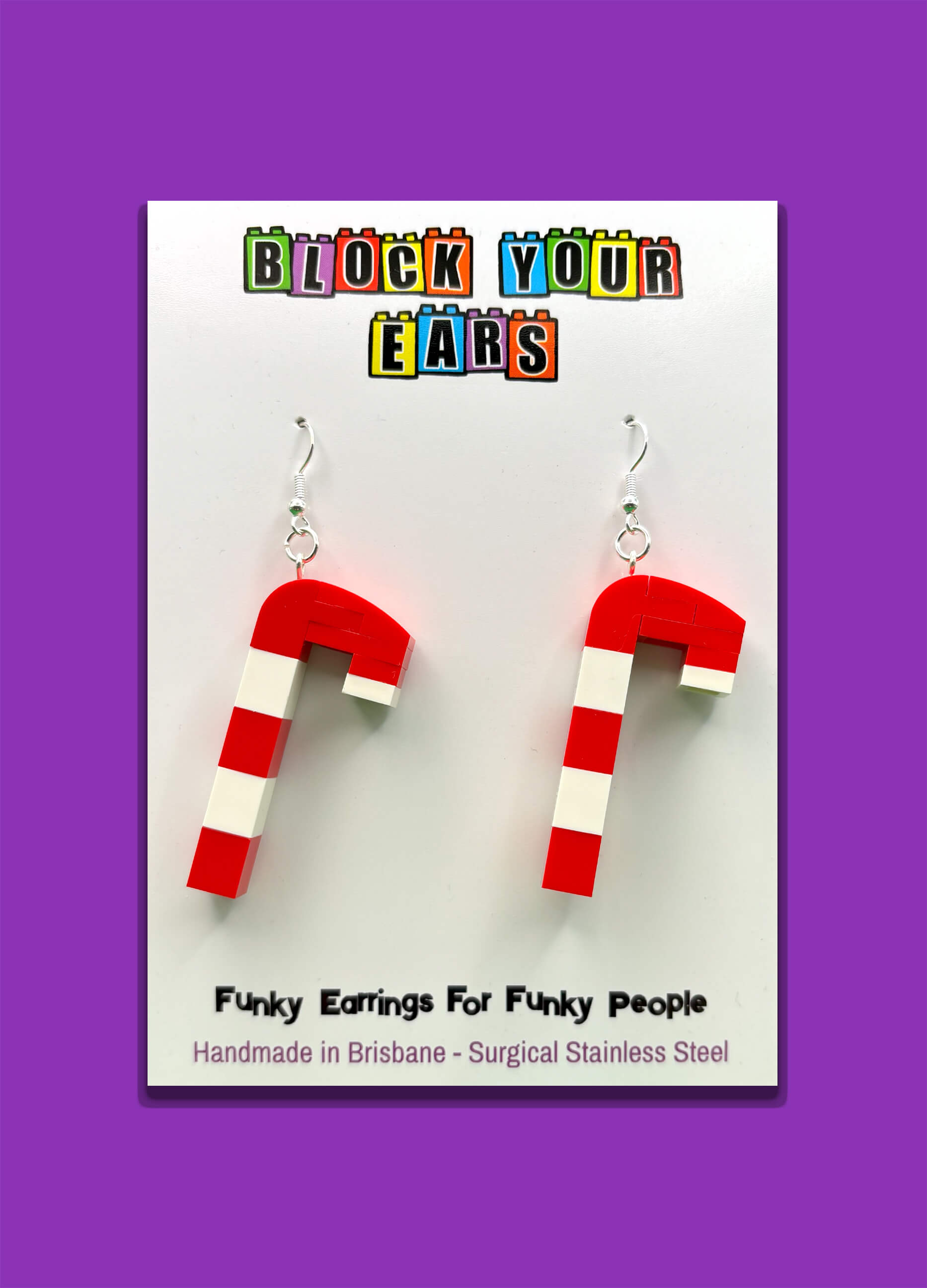 Handmade red and white LEGO candy cane earrings on display card with purple background