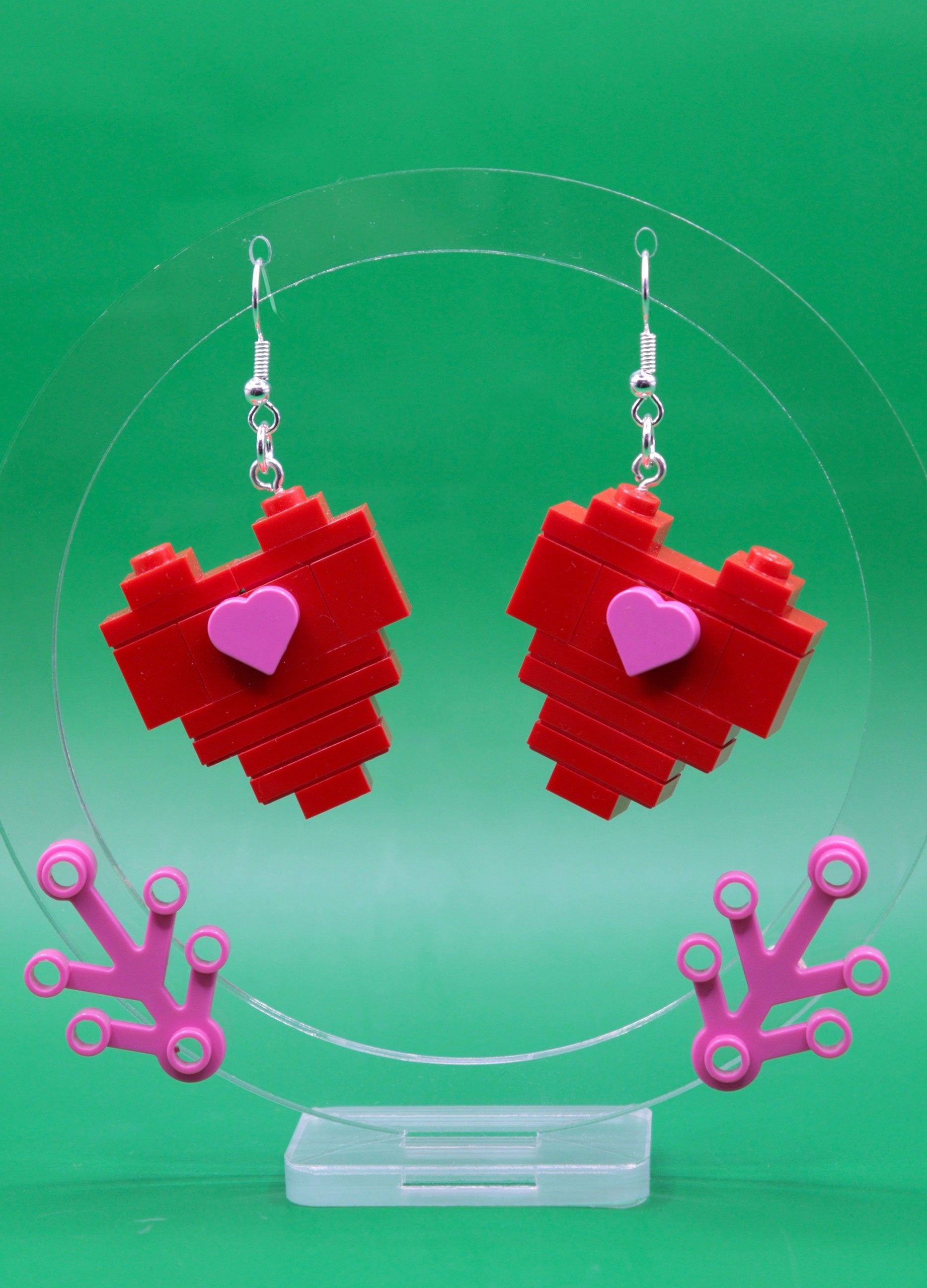 LEGO heart-shaped earrings with pink heart centres on a green background