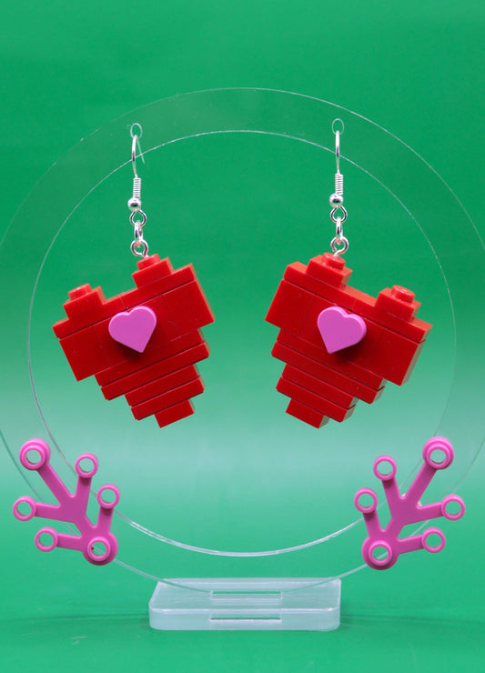 LEGO heart-shaped earrings with pink heart centres on a green background