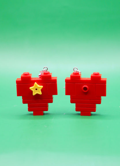 Red heart-shaped LEGO earrings with a yellow star on a green background
