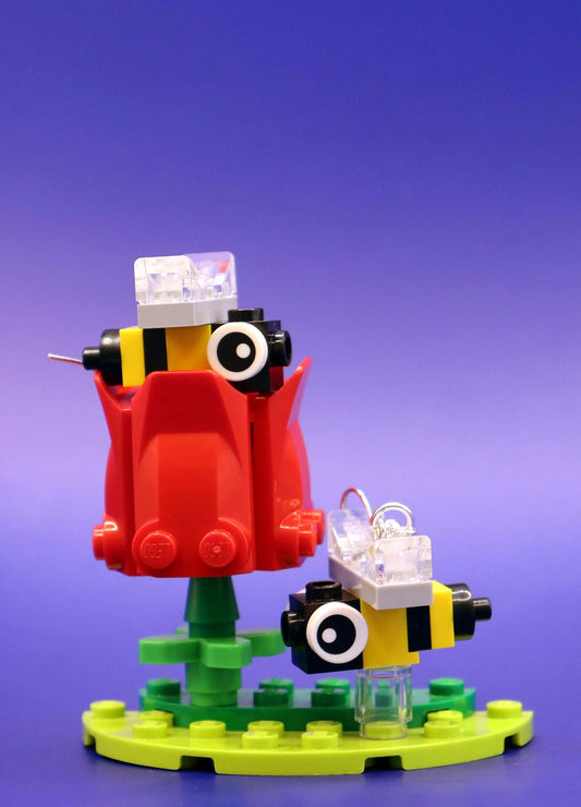 Close up of bee earrings on a red flower - handmade in Australia with LEGO bricks