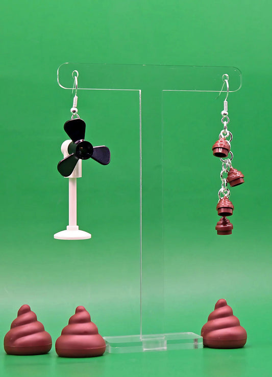 Chaos Incoming mismatched earrings – handmade fan and poo design using LEGO pieces, shown hanging on jewelry display