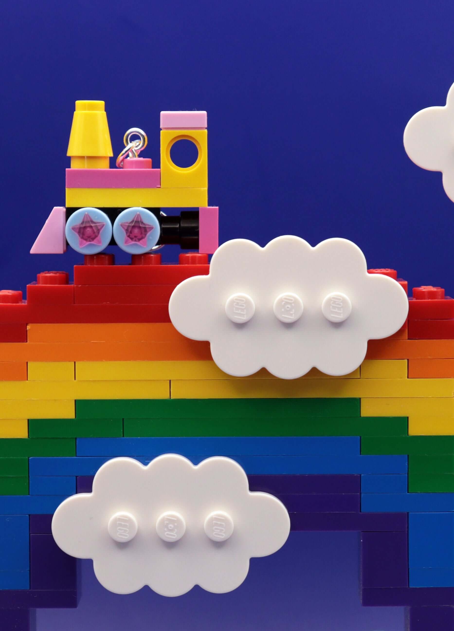 Close up of yellow and pink steam train earrings on a rainbow with clouds - handmade in Australia