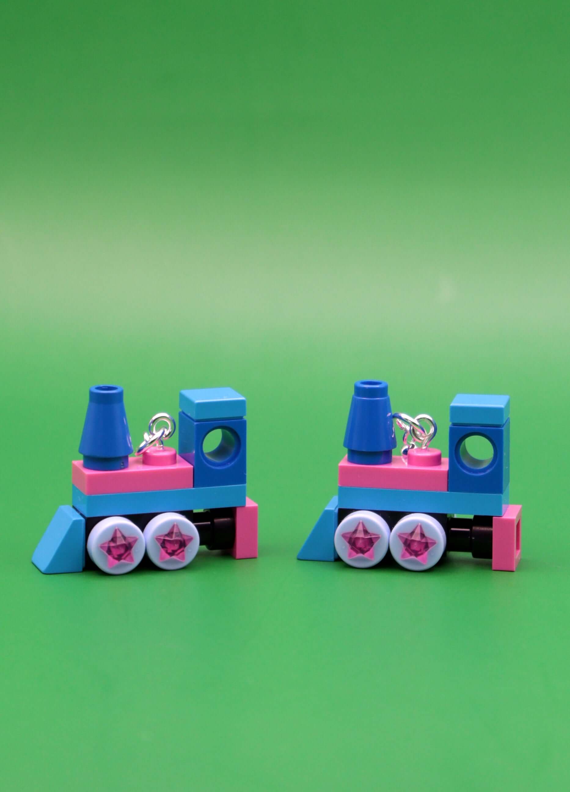 The Starlight Express– pink and blue LEGO earrings - close up miniature steam train on green background